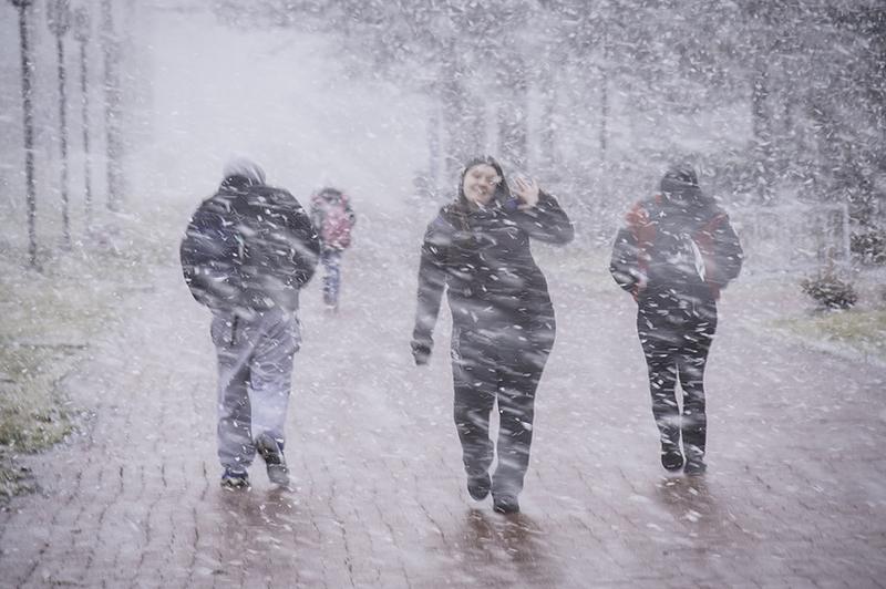 Four students walking outside during a blizzard